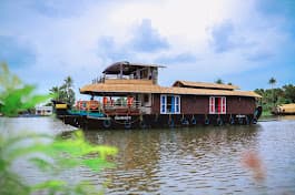 Sunset over Alappuzha backwaters with silhouette of a cruise houseboat
